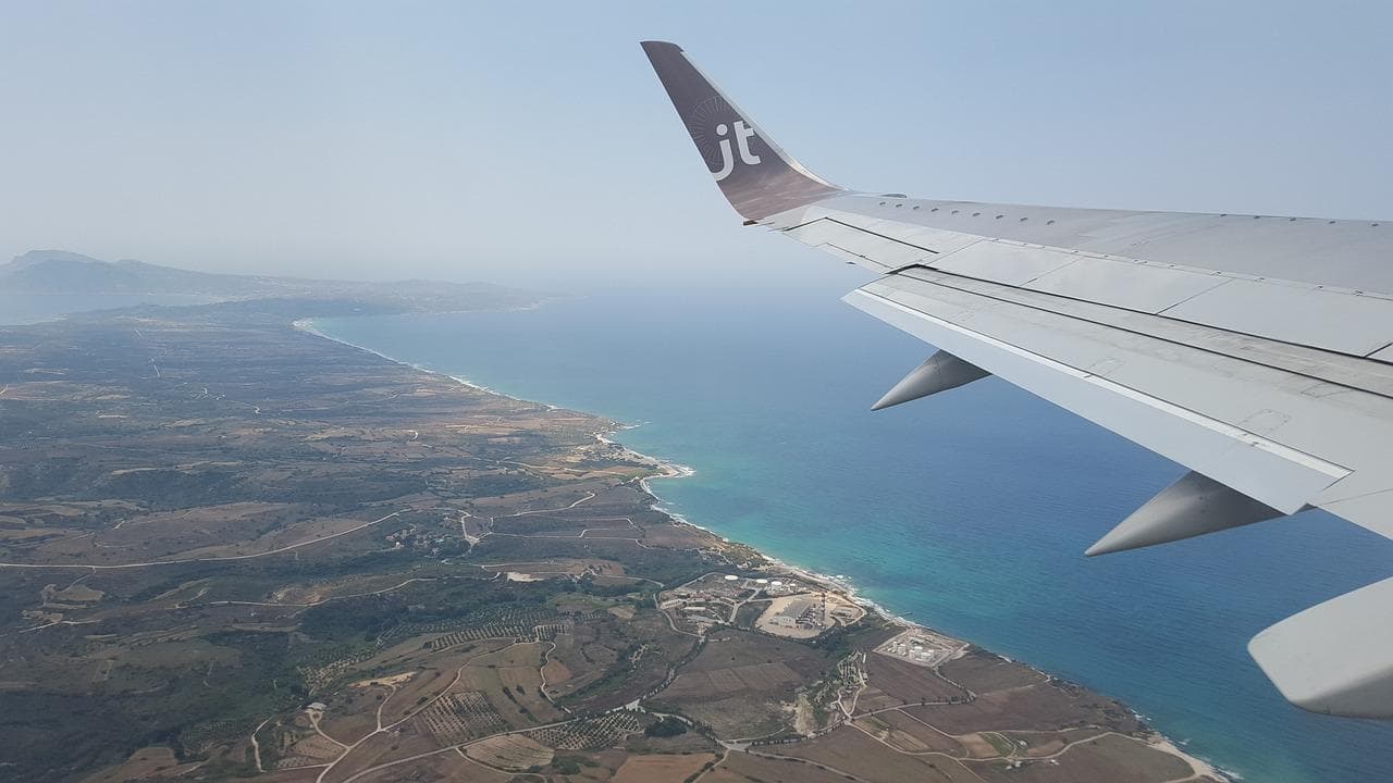 Pohled z letadla na Zakynthos. Dovolená, letiště, křídlo letadla, moře a pobřeží.