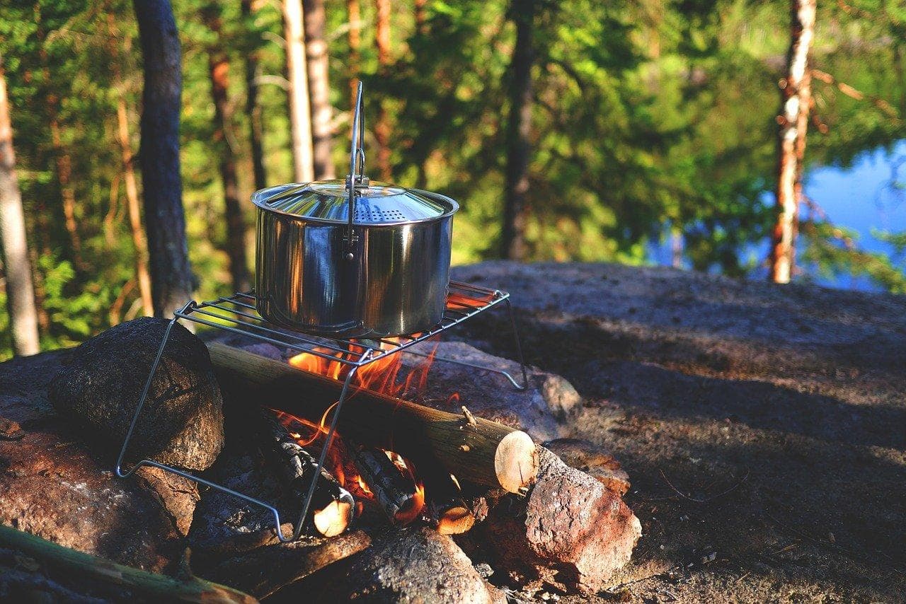 Vaření v přírodě. Kempingový hrnec nad ohněm v lese. Outdoorové vaření, turistika a dobrodružství.
