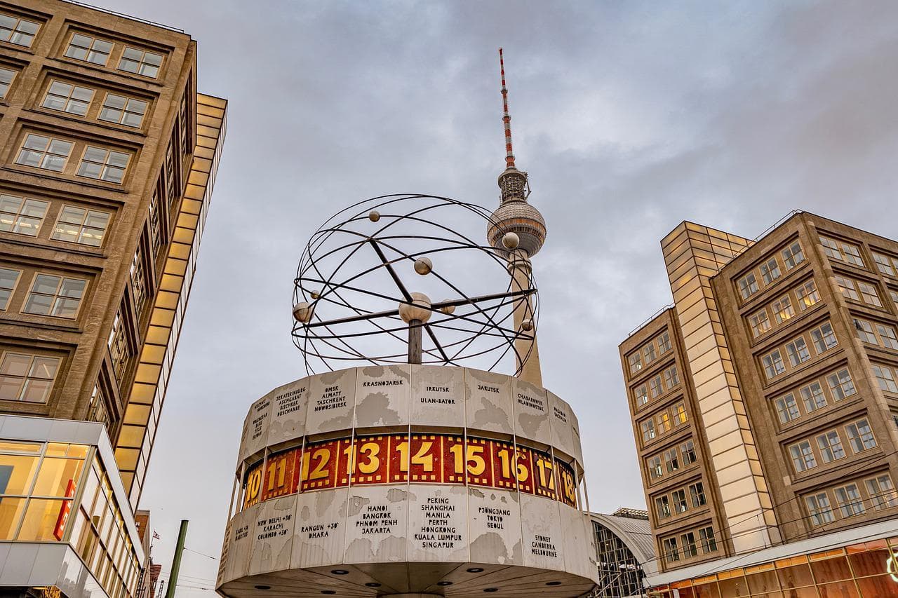 Berlín: Světové hodiny na Alexanderplatz s televizní věží v pozadí. Kosmopolitní centrum.
