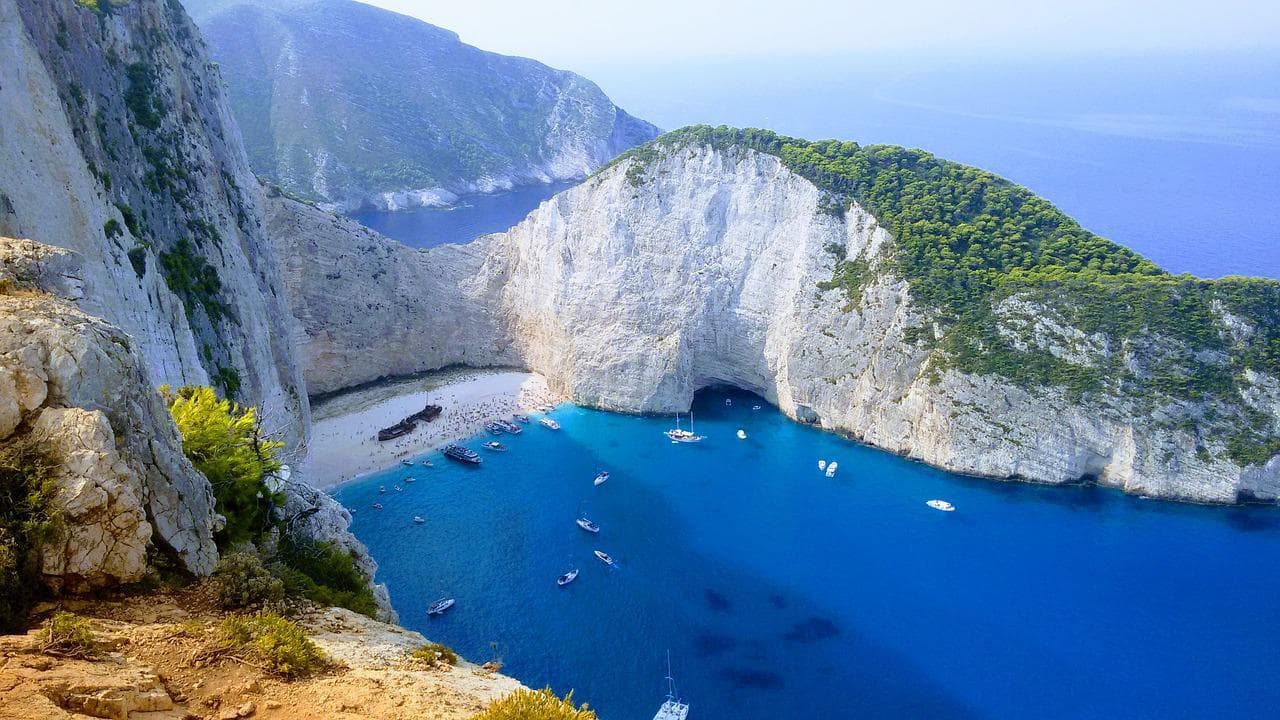 Pláž Navagio, Zakynthos. Tyrkysové moře, bílé útesy, vrak lodi na pláži. Dovolená v Řecku.