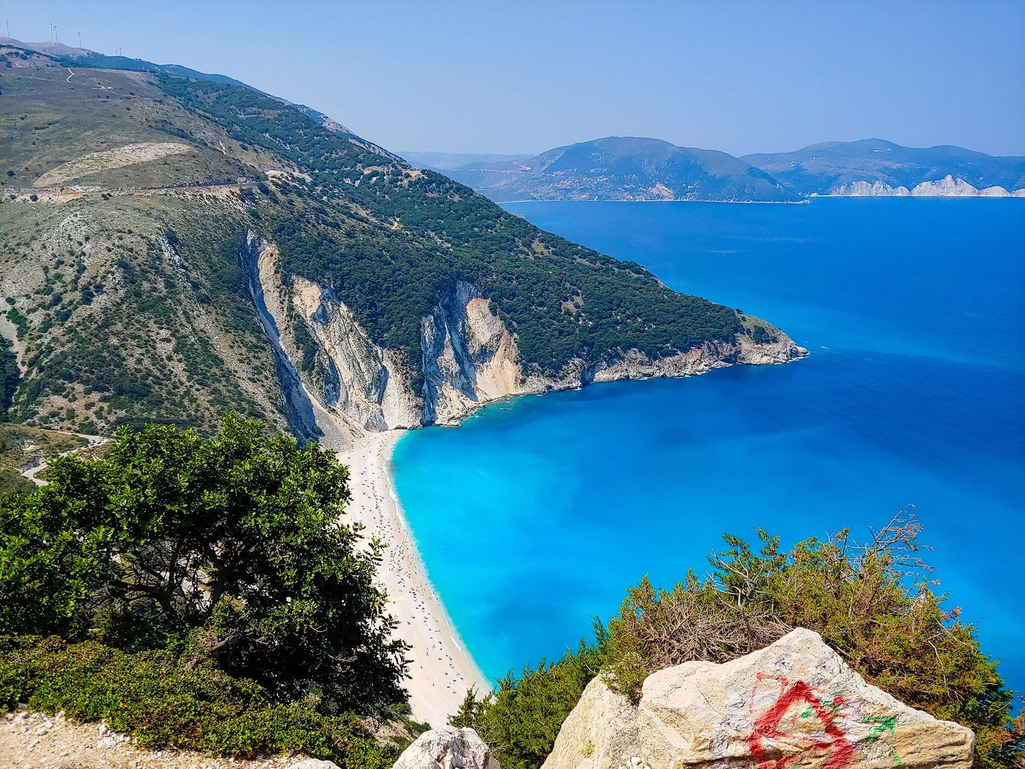 Jónské ostrovy: Pohled na pláž Myrtos, Kefalonie. Tyrkysové moře, hory a bílý písek. Dovolená v Řecku.