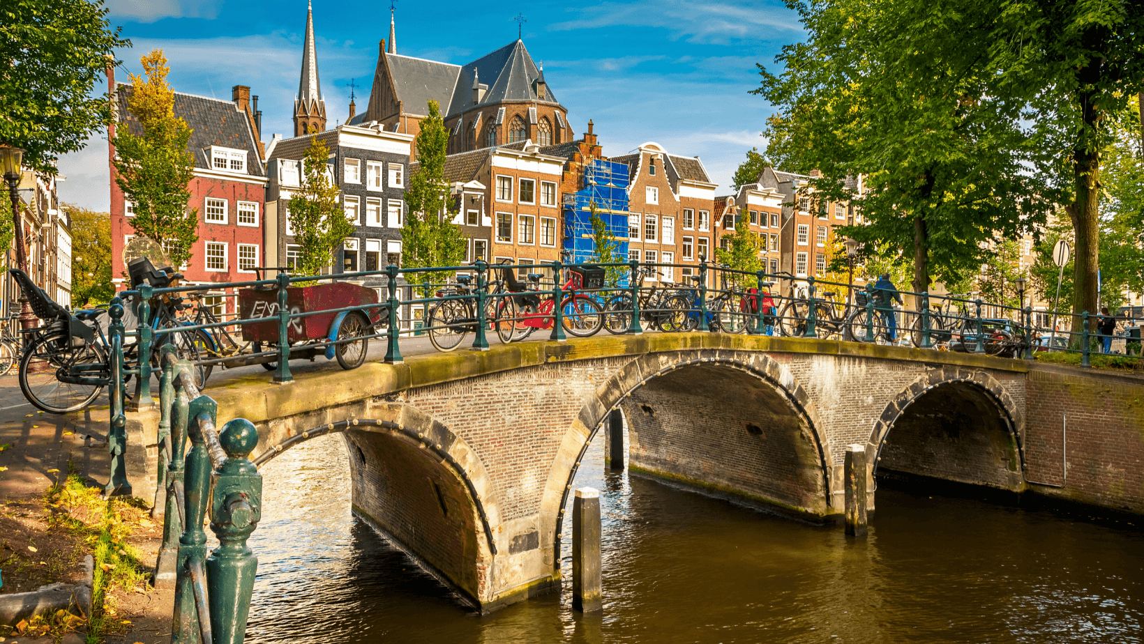 Amsterdam, Benátky severu. Kanál, most s koly a historické domy.