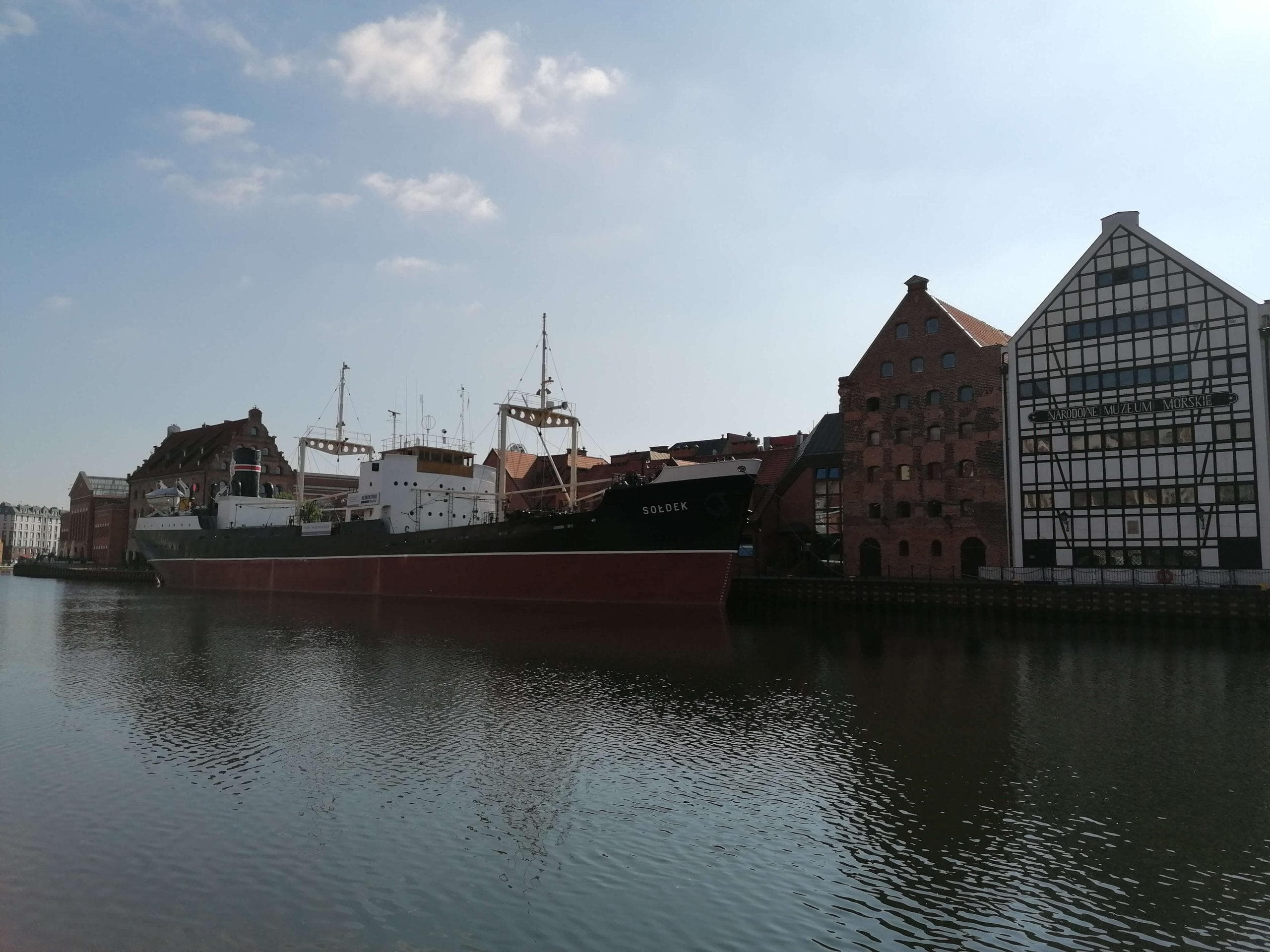 Gdaňsk, Polsko: Loď na řece Motława s historickými budovami. Cestování, architektura.
