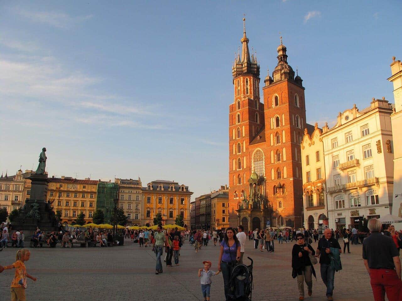 Krakov, Polsko: Mariánský kostel na hlavním náměstí. Turisté a architektura v centru Krakova.