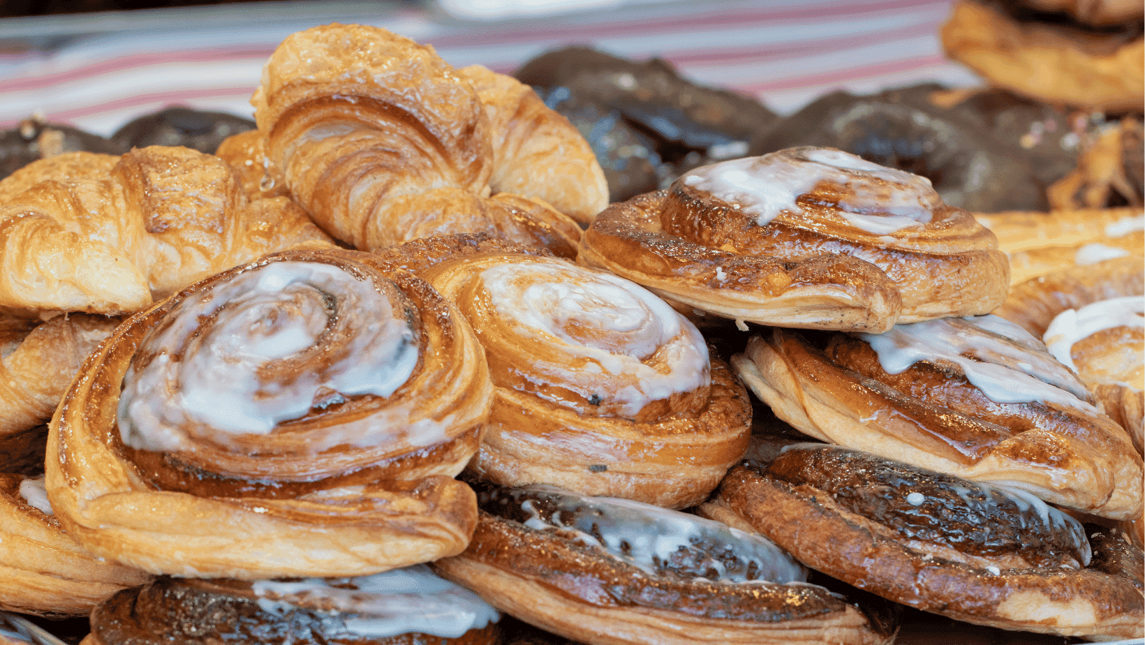 Čerstvé sladké pečivo. Skořicové rolky a croissanty s polevou. Lahodné dobroty z pekárny.