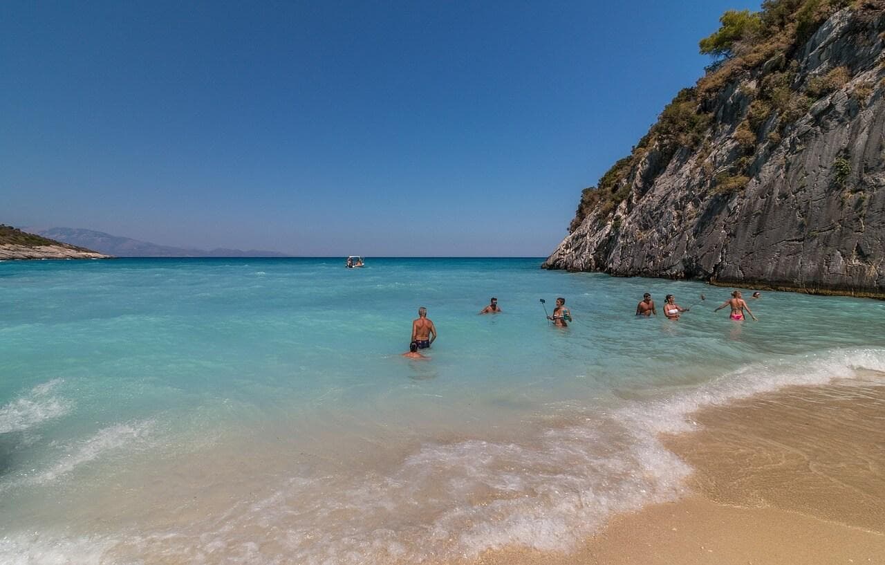 Pláž Xigia Zakynthos: Lidé se koupou v tyrkysovém moři u pláže s útesy. Dovolená v Řecku.