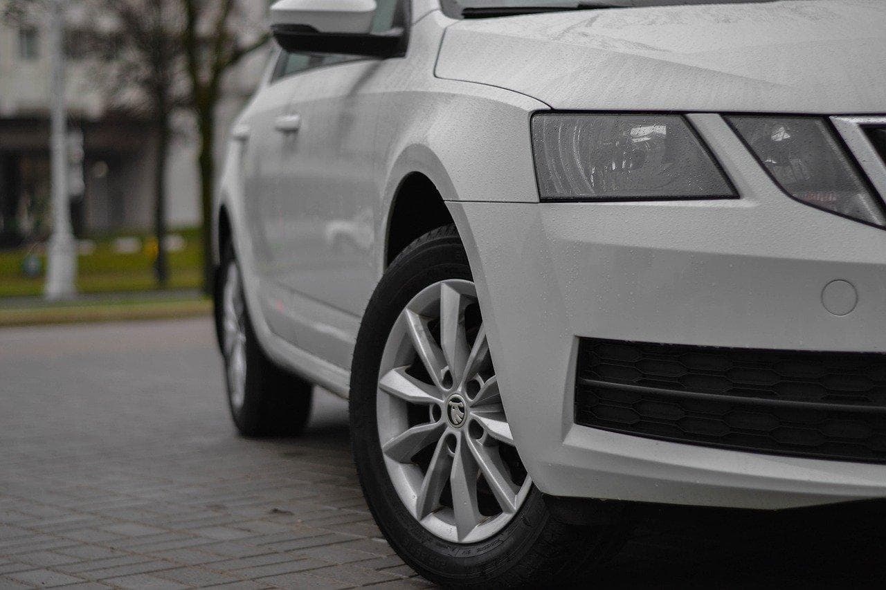 Bílá Škoda Octavia, ideální auto na rodinné cesty. Detail na kolo a světlo.