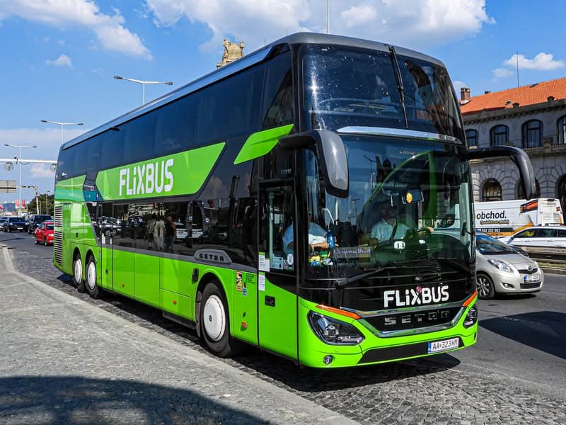 Zelený autobus Flixbus na ulici. Akce na jízdenky od 99 Kč. Levné cestování autobusem.
