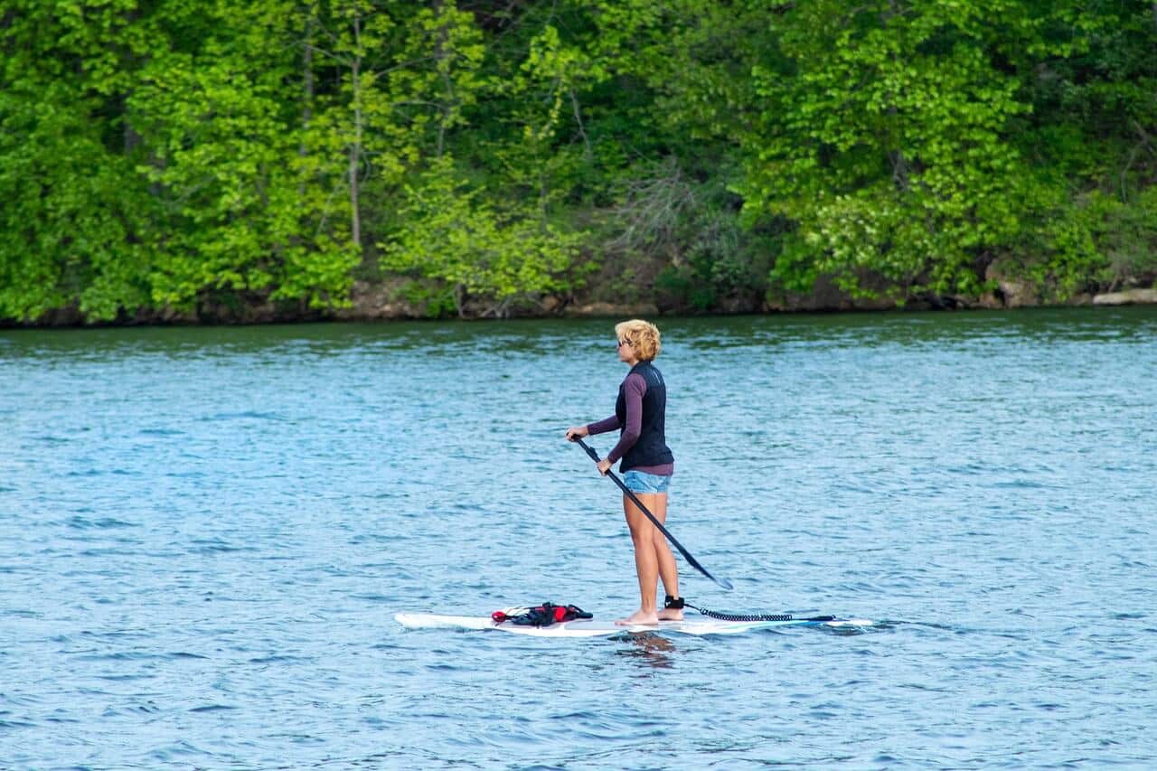 Žena na paddleboardu na jezeře. Vodní sporty, rekreace. Jak vybrat paddleboard.