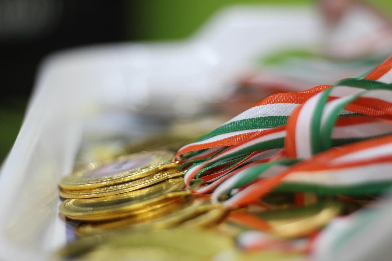 Detailní pohled na zlaté olympijské medaile s trikolorou. Symbol úspěchu a sportovního ducha, olympijské ocenění.