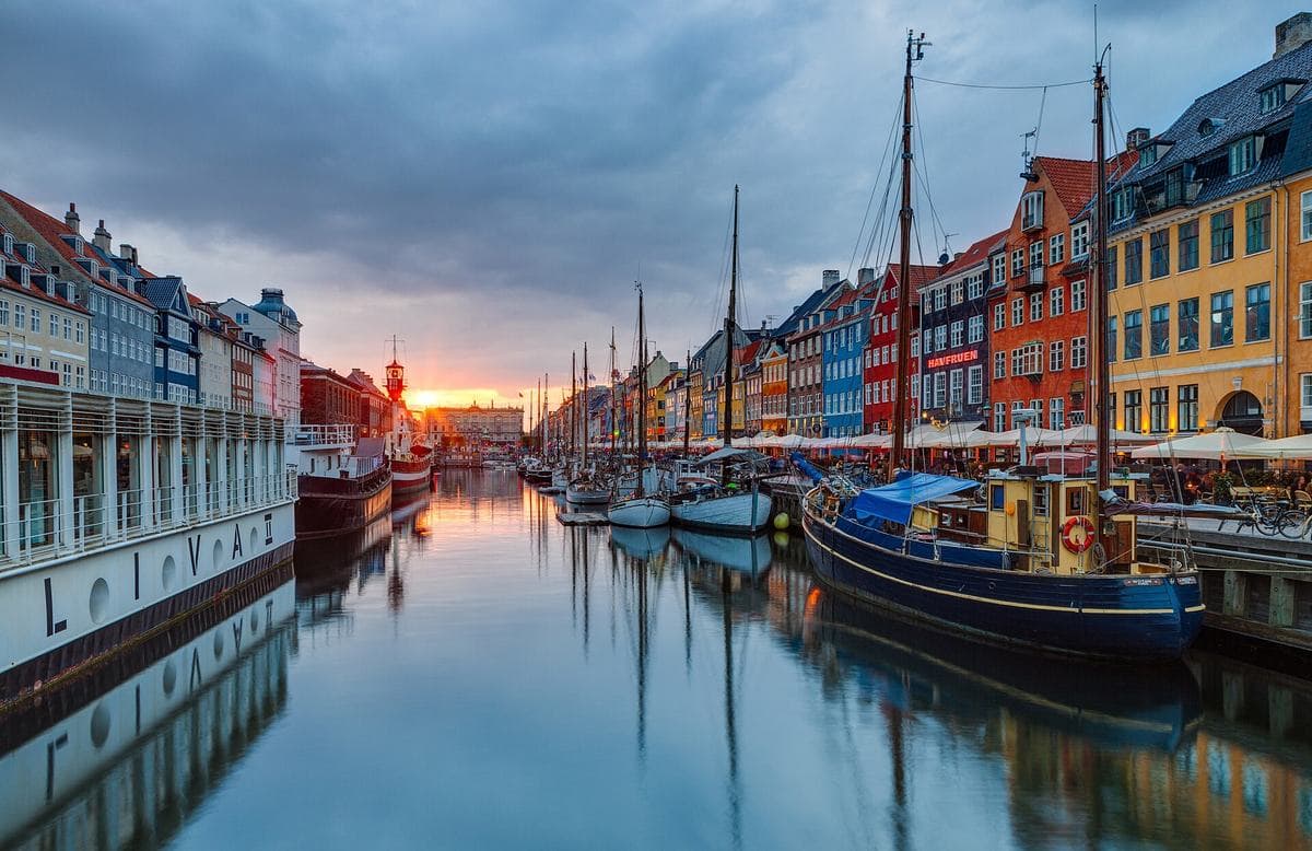 Barevné domy a plachetnice v přístavu Nyhavn v Kodani při západu slunce