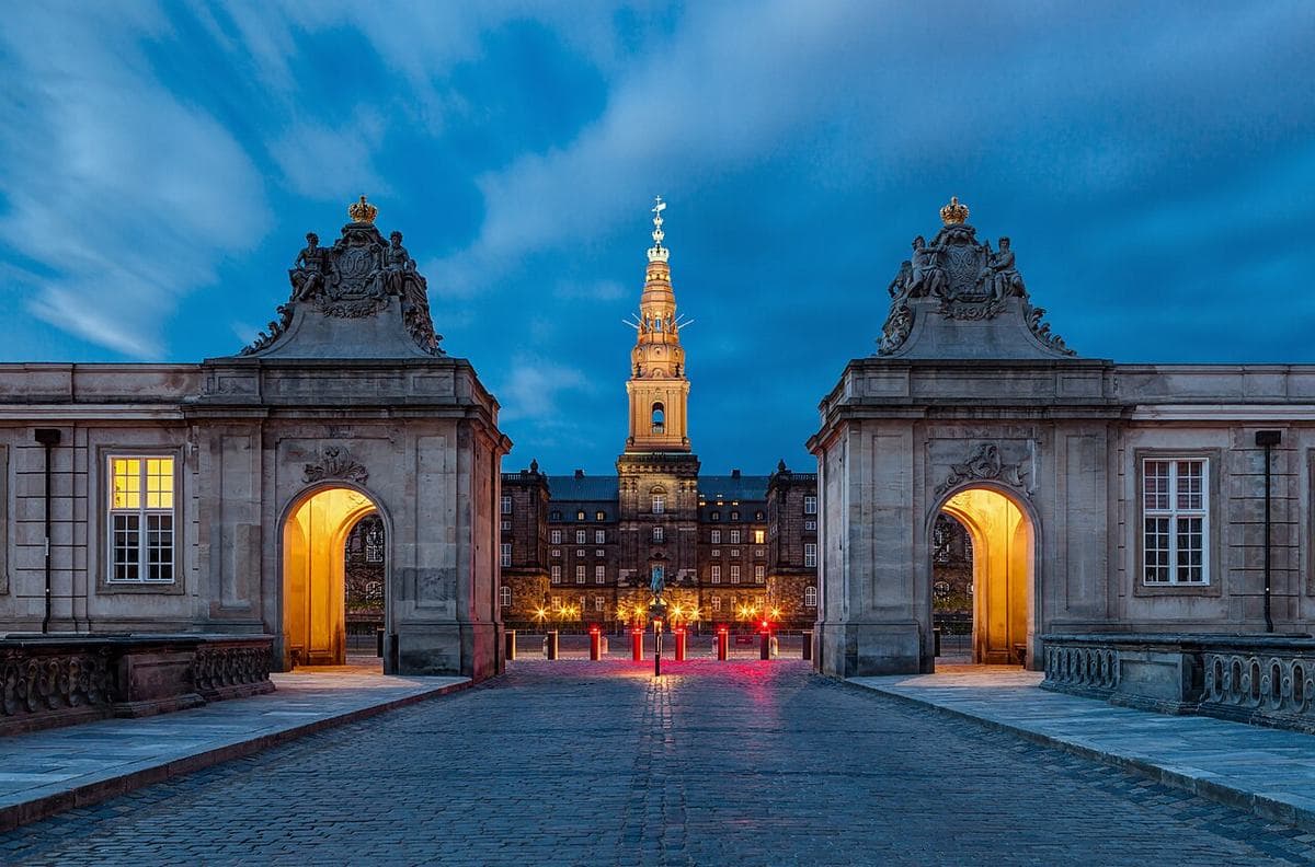 Zámek Christiansborg v Kodani večer, osvětlené brány a věž