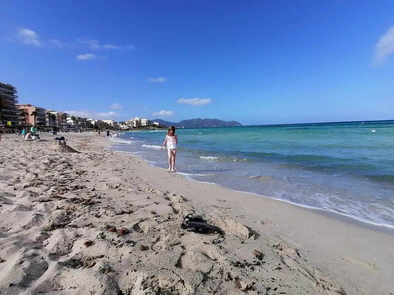 Písečná pláž v Cala Millor s hotely a horami v pozadí