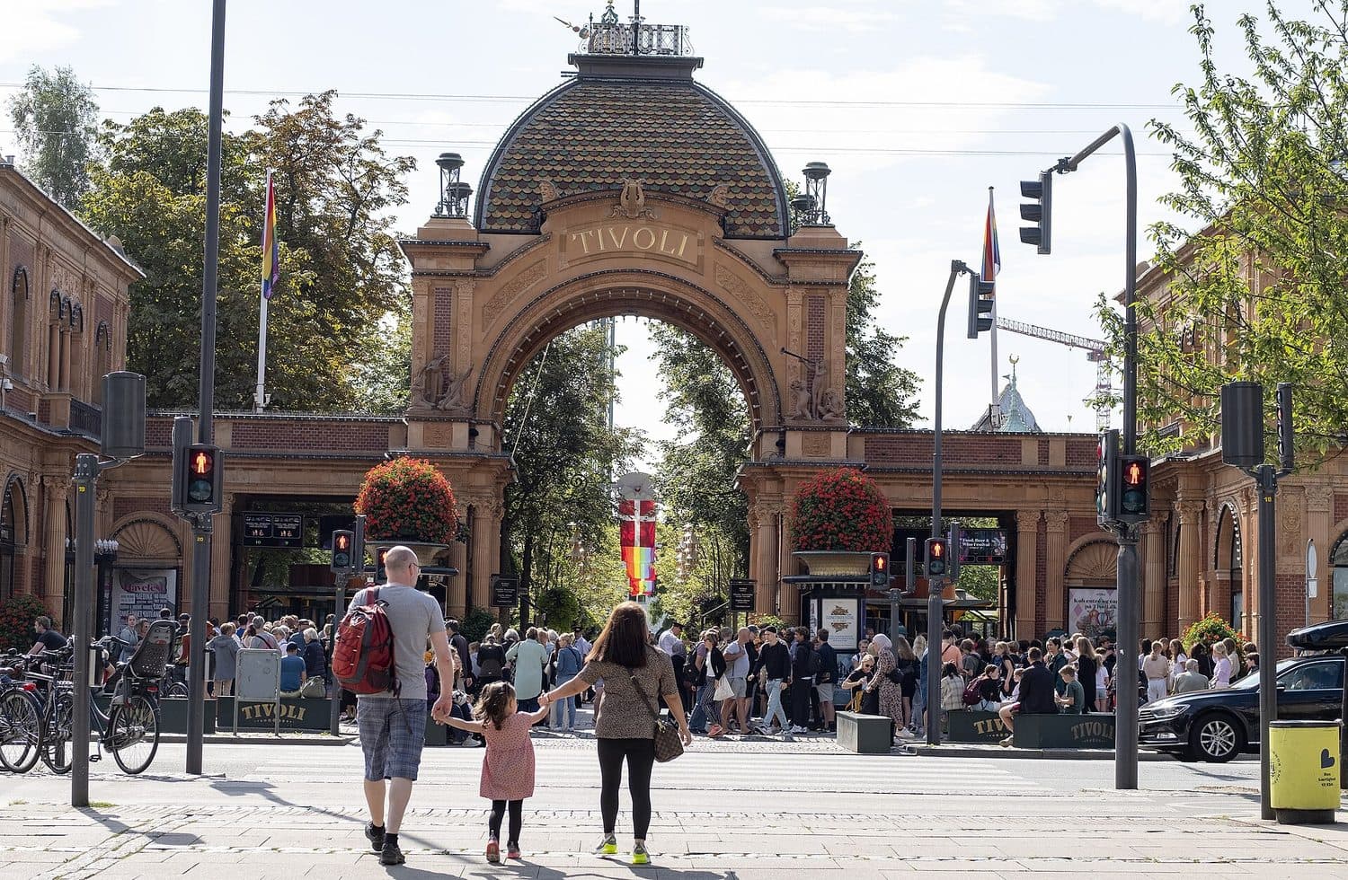 Hlavní vchod do Tivoli z Vesterbrogade, oblouk s nápisem Tivoli, před ním rodina s holčičkou na přechodu a fronta lidí