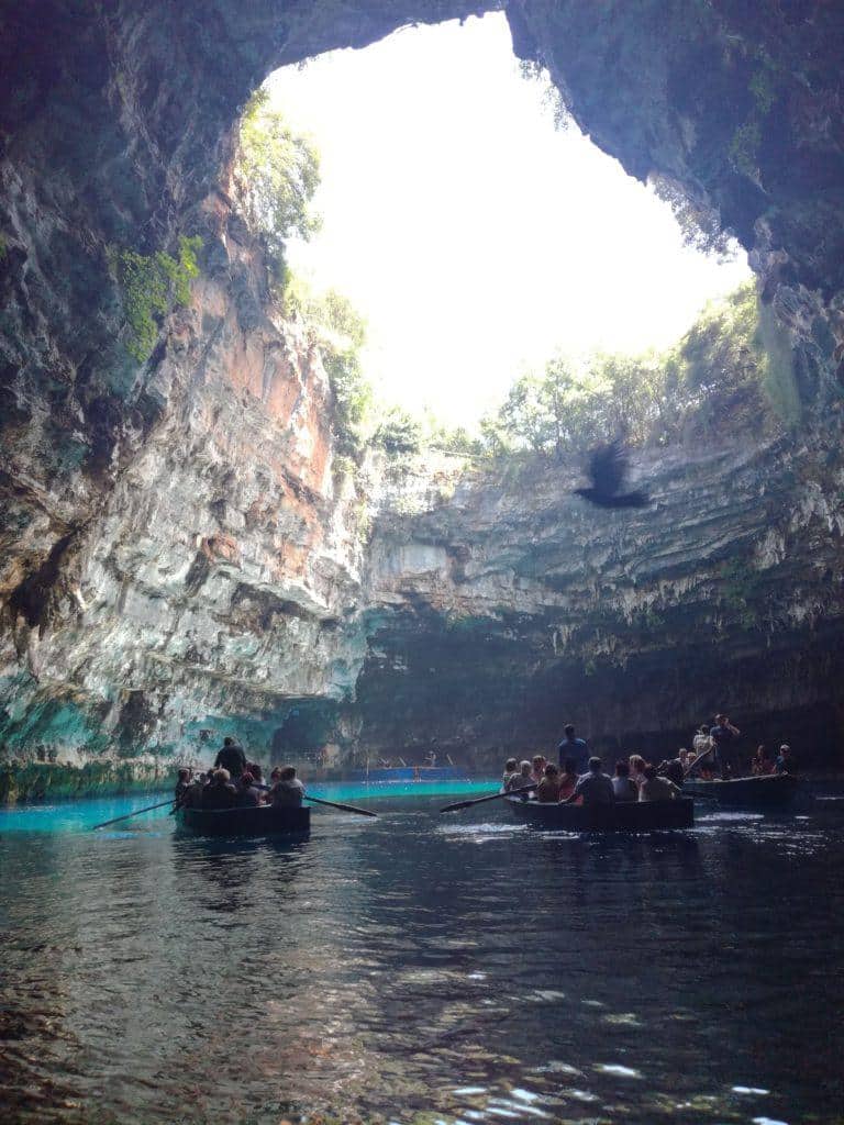 Loďky s turisty na tyrkysovém jezeře v jeskyni Melissani pod otvorem ve stropě