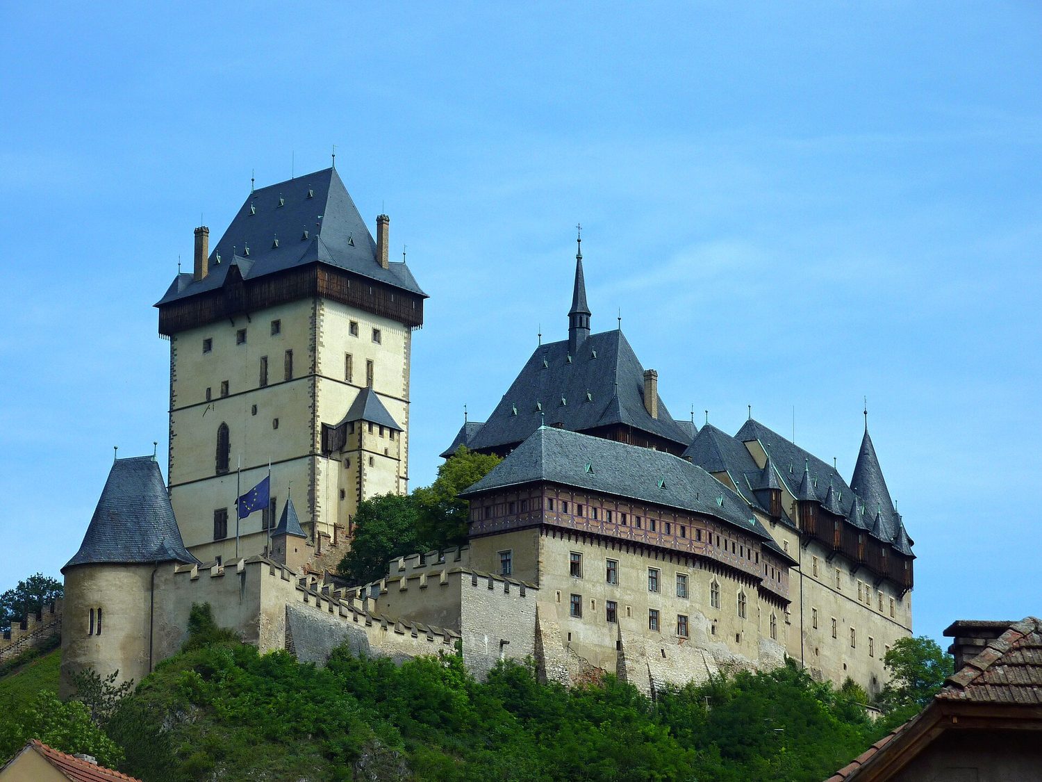 Hrad Karlštejn nad střechami obce za slunečného dne