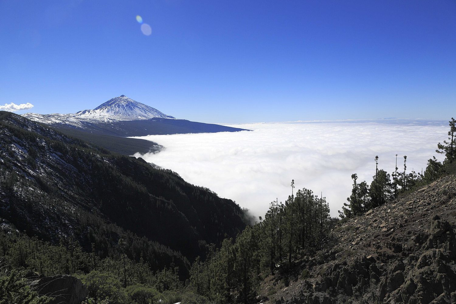Pasátová oblaka nad severními svahy Tenerife a zasněžená sopka Teide v únoru