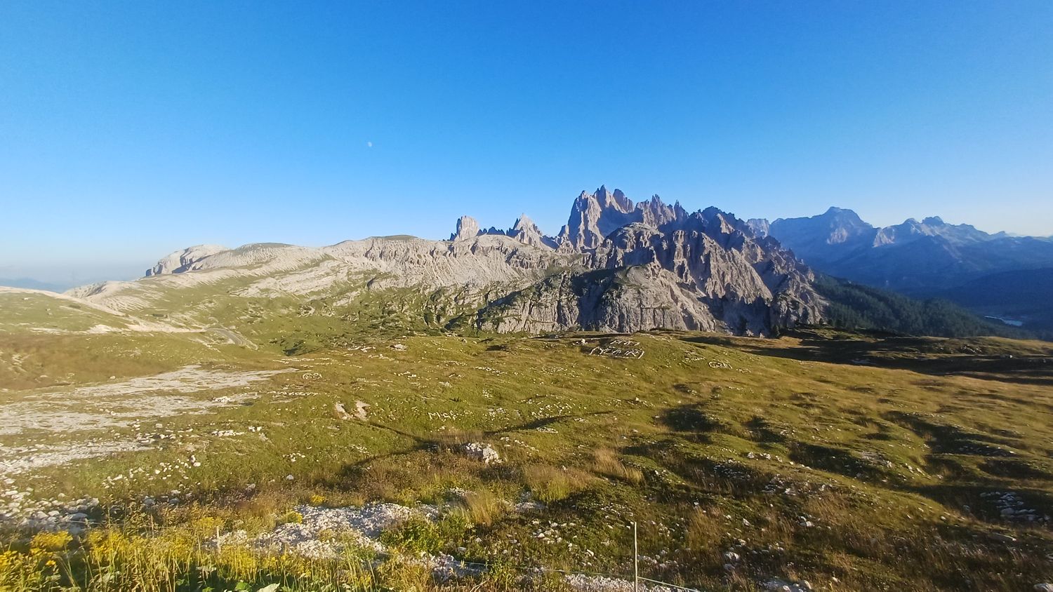 Louka u parkoviště Tre Cime a skalní hřeben naproti ve večerním světle