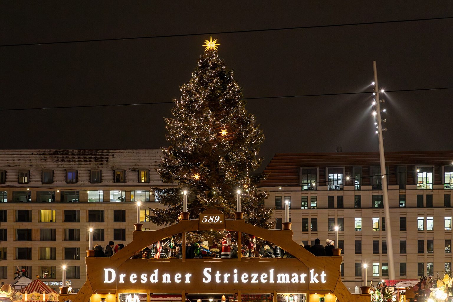 Vánoční strom a nasvícená pyramida s nápisem Dresdner Striezelmarkt večer na Altmarktu