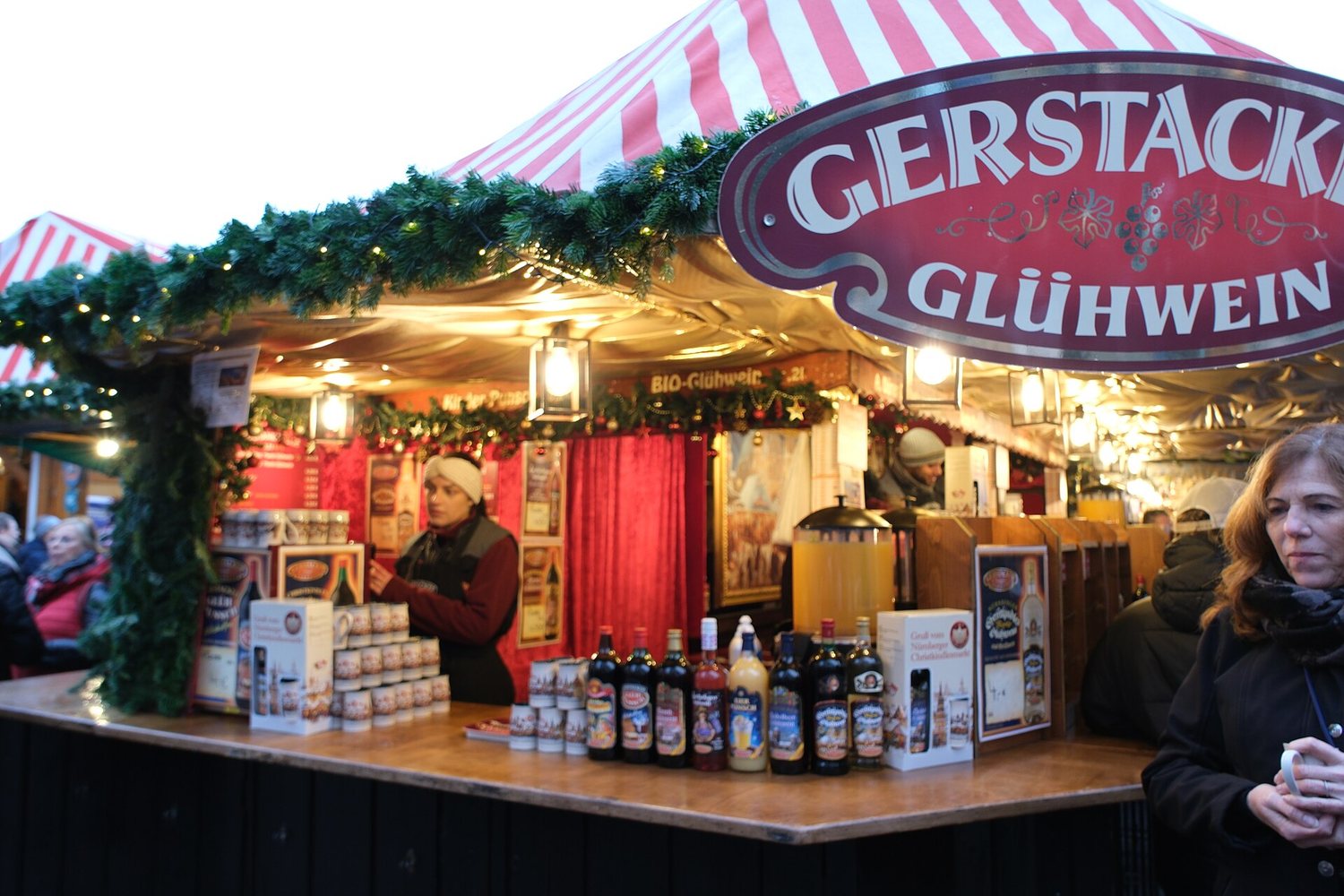 Stánek s vínem a svařákem pod červenobílou střechou na Christkindlesmarktu v Norimberku