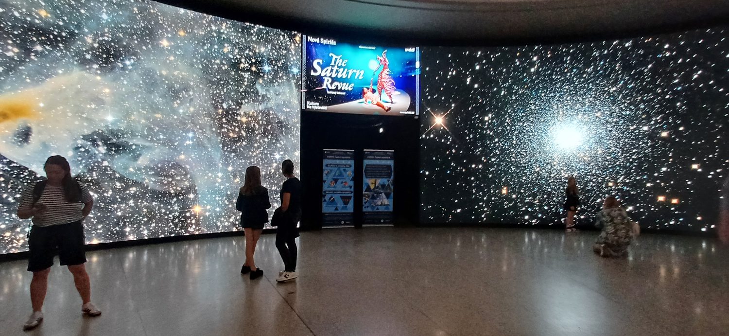 LED stěny ve foyer Planetária Praha s hvězdokupami a plakátem na pořad The Saturn Revue