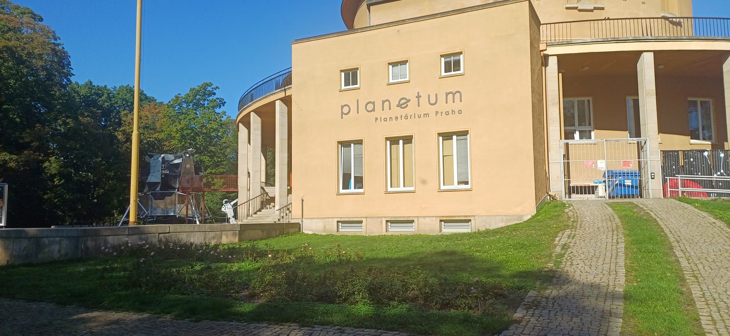 Vstupní část budovy Planetária Praha s nápisem planetum a modelem kosmického modulu vlevo