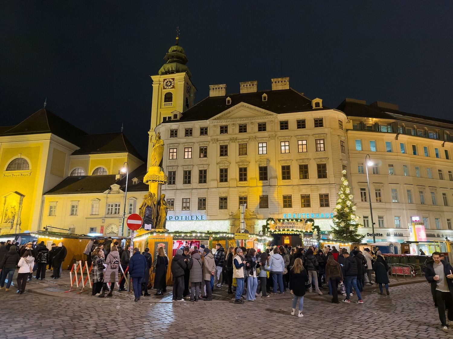 Altvídeňský vánoční trh na náměstí Freyung večer, stánky a lidé před barokními domy